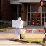 Man seen on college campus wearing white hood, carrying sign with racist comments