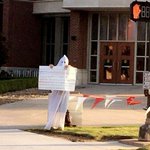 Man seen on college campus wearing white hood, carrying sign with racist comments