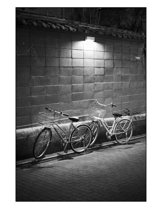 GE こんばんは。古風な塀に似つかわしくないライトと自転車。とはいえこれがこの町の日常。この雑多な感じがその町の生活を感