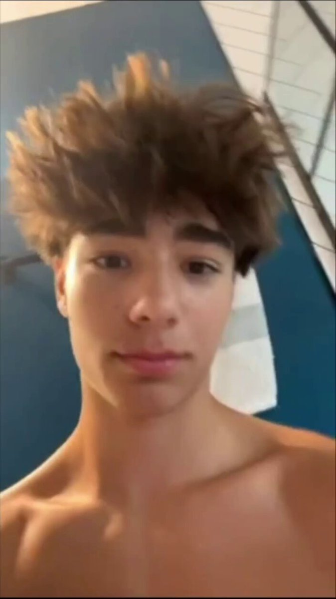 A man in a white shirt and sunglasses smirks at the camera