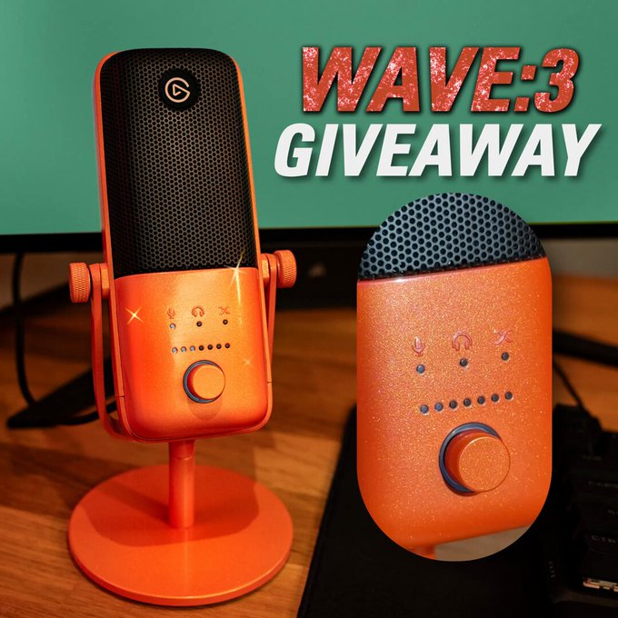 An orange glitter microphone with a black mesh head and control buttons sits on a wooden desk accompanied by a matching orange glitter device with a similar design The microphone is mounted on a circular orange base with adjustable joints while the smaller device features a large orange knob and LED indicators A computer monitor and keyboard are visible in the background suggesting a tech setup The text WAVE3 GIVEAWAY in red and white appears prominently in the upper right corner overlaying the scene