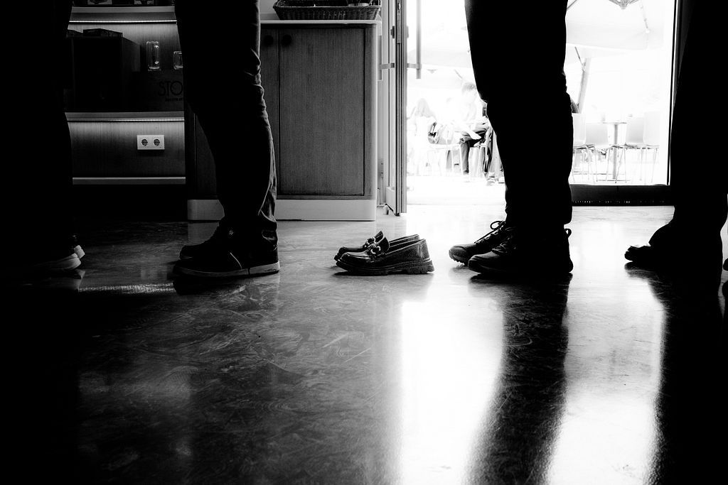 _Travelfox_'s tweet card. Everyone is waiting. Legs steady, feet firm. Yet in the middle of this everyday queue, a pair of shoes waits too — without a wearer. Are they left behind?...