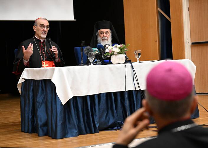 americamag's tweet card. Cardinal Pizzaballa and Patriarch Theophilos III gave a press conference after visiting the Holy Family Parish church, which was struck by Israeli forces.