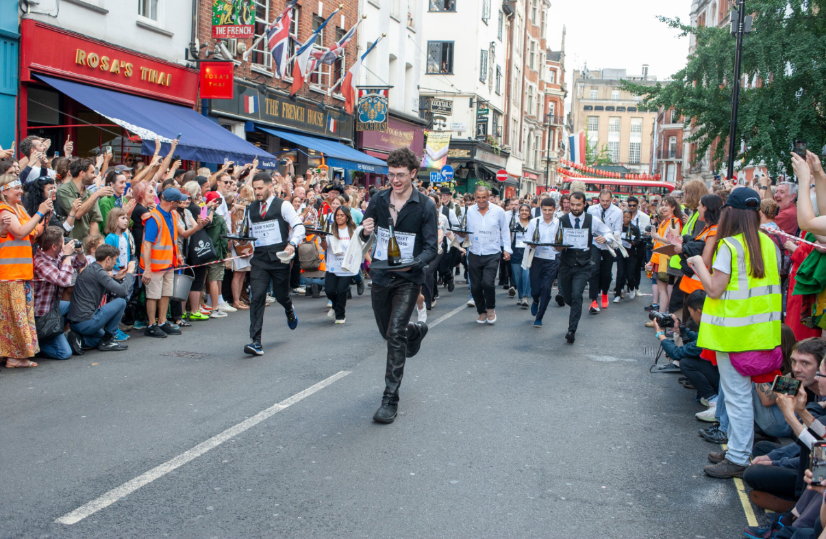 SohoGeorge's tweet card. The rain clouds cleared and Soho’s community turned out in style, to celebrate the 50th Soho Village Fete organised by the Soho Society, in St Anne’s Gardens, Wardour Street, on Sunday. The Jubilee...