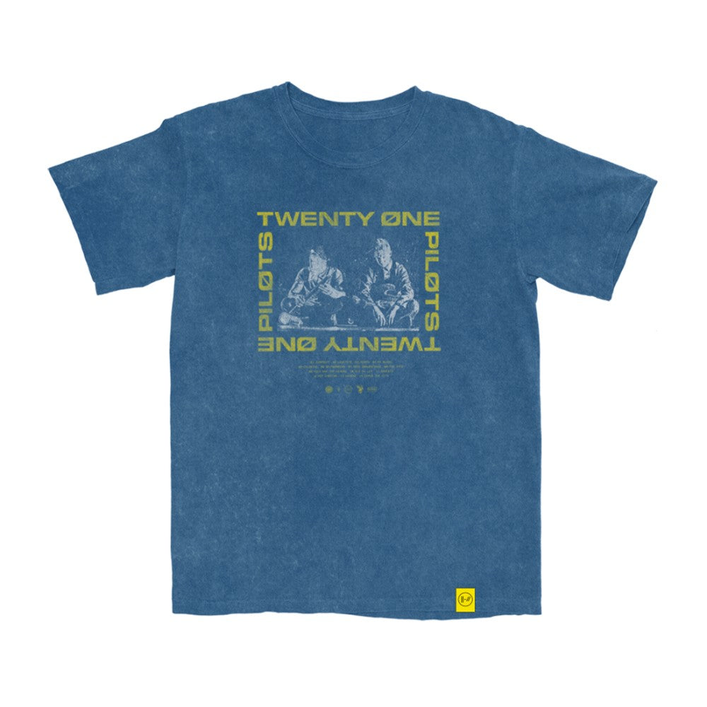 TOPMerchAlerts's tweet card. The Twenty One Pilots 'Sit Block T-Shirt' features an image of the band with a yellow 'Twenty One Pilots' logo around it on the front of the shirt. This design is printed on a blue unisex t-shirt. 