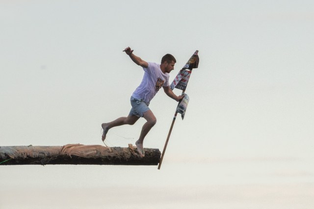 joedwinell's tweet card. A 45-foot long telephone pole, dripping with grease, juts off a pier 200 feet off Gloucester’s Pavilion Beach and people just can’t wait to run it.
