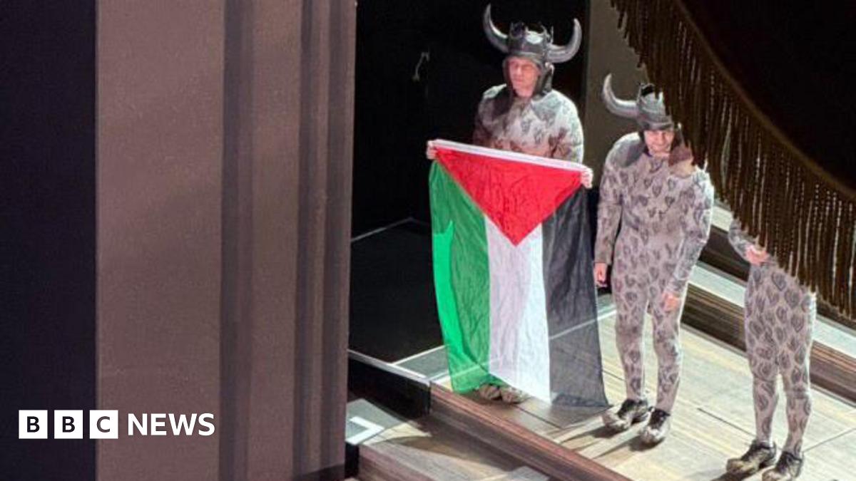 jsdhenderson's tweet card. A cast member unfurls a Palestinian flag during a curtain call, prompting a brief scuffle as an official tries to take it away.