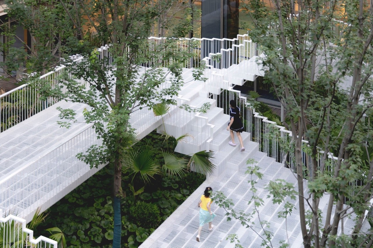 DomusWeb's tweet card. A project developed around a nine-meter recessed courtyard transforms vertical circulation into a spatial and relational experience.
