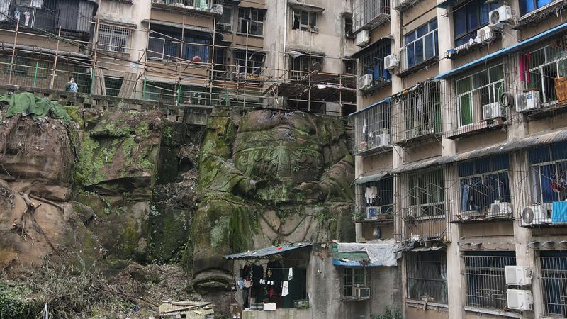CNNStyle's tweet card. For years, residents in an old neighborhood of Chongqing, southwest China, have walked past two apartment buildings built onto a steep slope, oblivious to what lay beneath: a giant statue carved into...