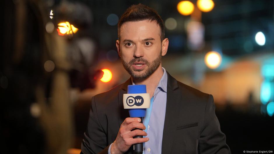 dwnews's tweet card. German police are still investigating a brutal attack on DW reporter Adonis Alkhaled, a year after the incident at a concert by Syrian star Al Shami in Germany.