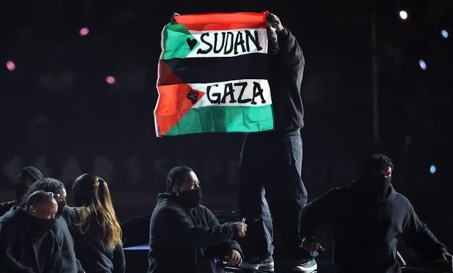 IMChq's tweet card. Explore the controversy surrounding Kendrick Lamar's Super Bowl halftime show involving a protest flag and dancer Zul-Qarnain Kwame Nantambu.