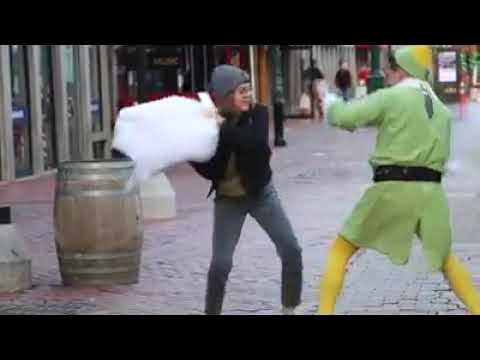 ProfJoeKim's tweet card. Firefighter dressed as Buddy the Elf challenges strangers to pillow...