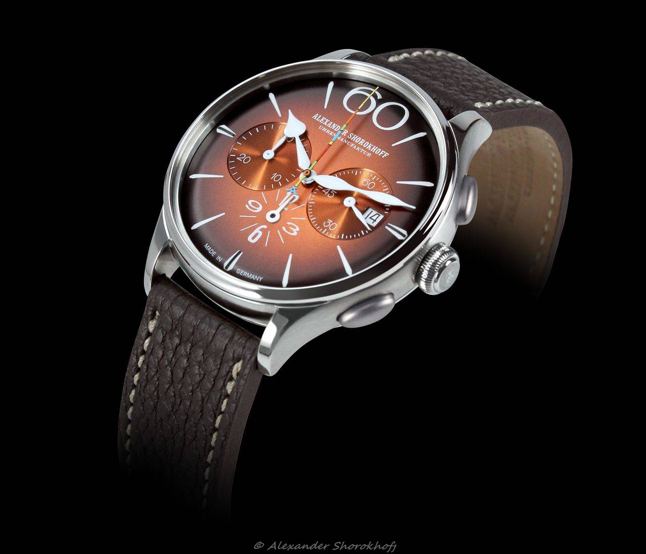 Uhrmacherkunst's tweet card. Der Chronograph „Happy Second Orange“ erstrahlt mit einem Zifferblatt in einem warmen Retro-Orange, das seitlich in Dunkelbraun übergeht.