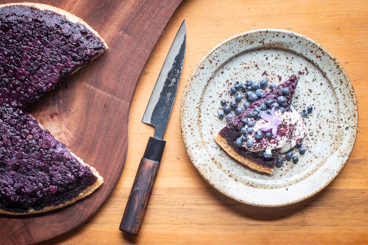 AlanBergo's tweet card. A rich cake made with hazelnut meal soaked with wild blueberry juice topped with almond-scented meadowsweet cream tastes like the peak of summer.