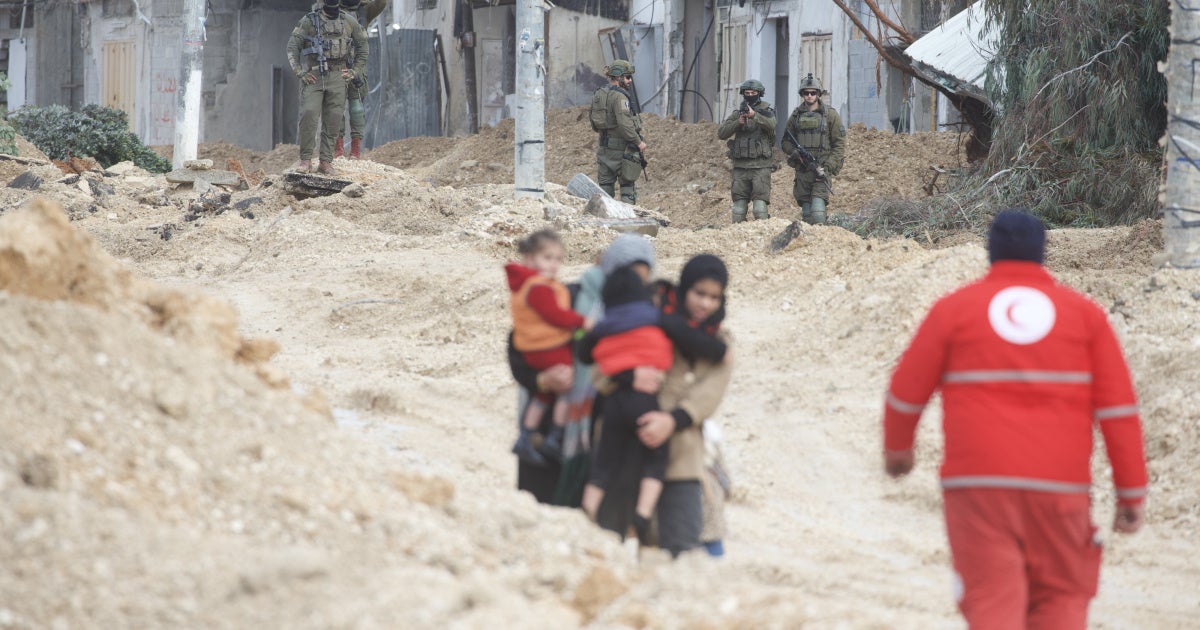Women carry children as Israeli forces forcibly displace them from Nur Shams refugee camp
