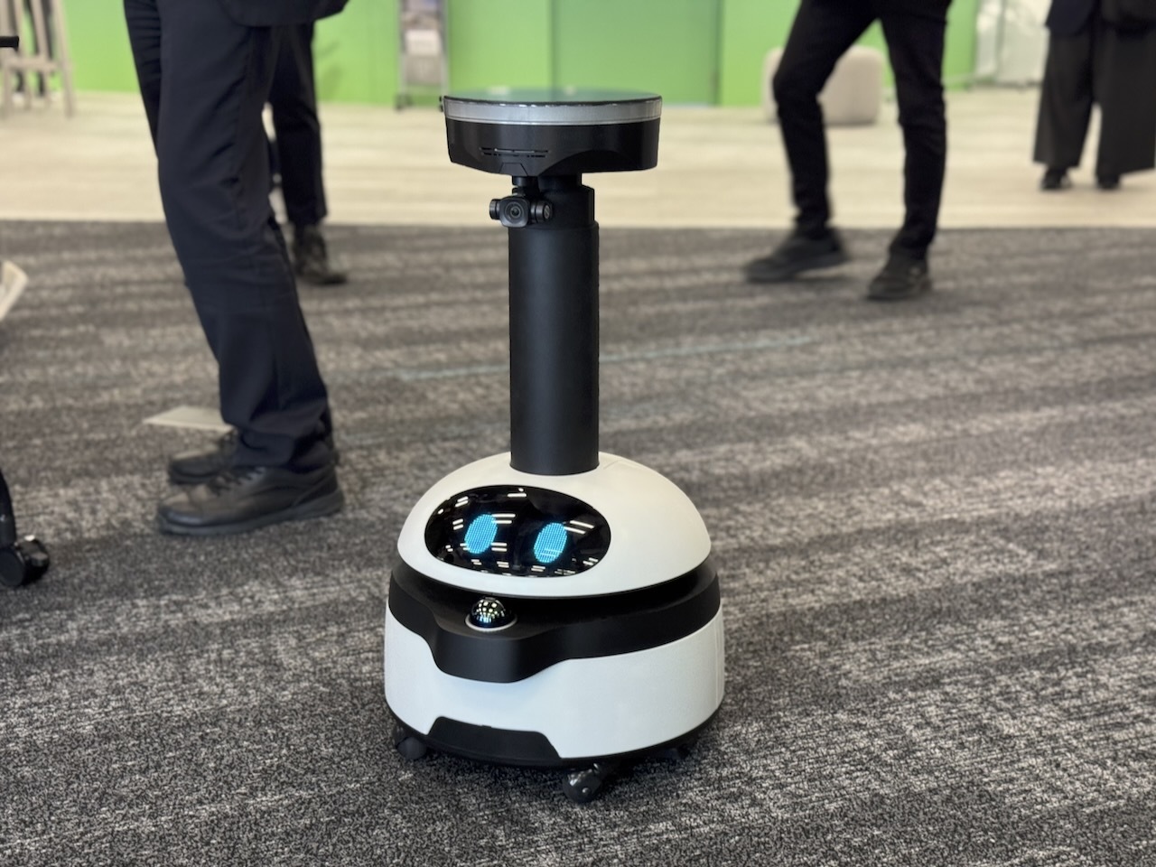 cnet_japan's tweet card. パナソニック エレクトリックワークス社は10月9日、警備・点検ロボットを手がけるugoと共同で、スマートビル向けにサービスロボット運用効率を高める技術検証を2025年9月から開始すると発表した。天井に設置したビーコン付き照明の信号を活用し、ロボットの自己位置推定や自動復旧機能の実現を目指す。