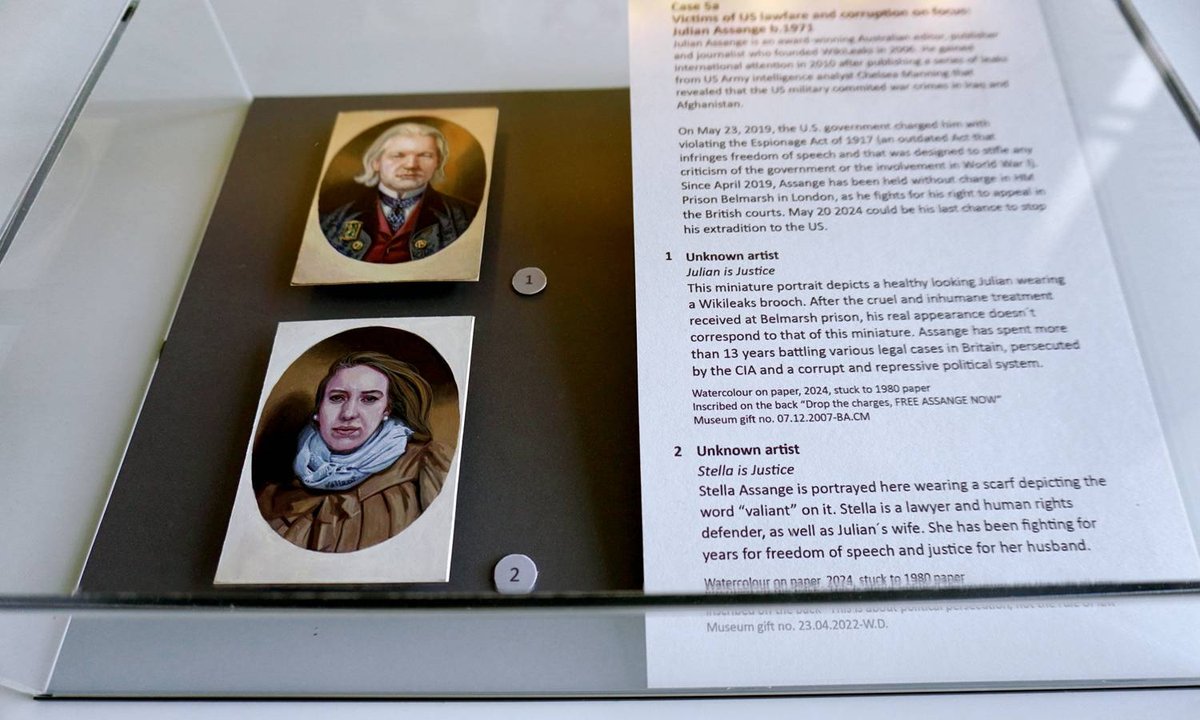 AssangeDAO_Fans's tweet card. Hand-painted portraits of the WikiLeaks founder and his wife Stella were smuggled into a display case at the London museum in April