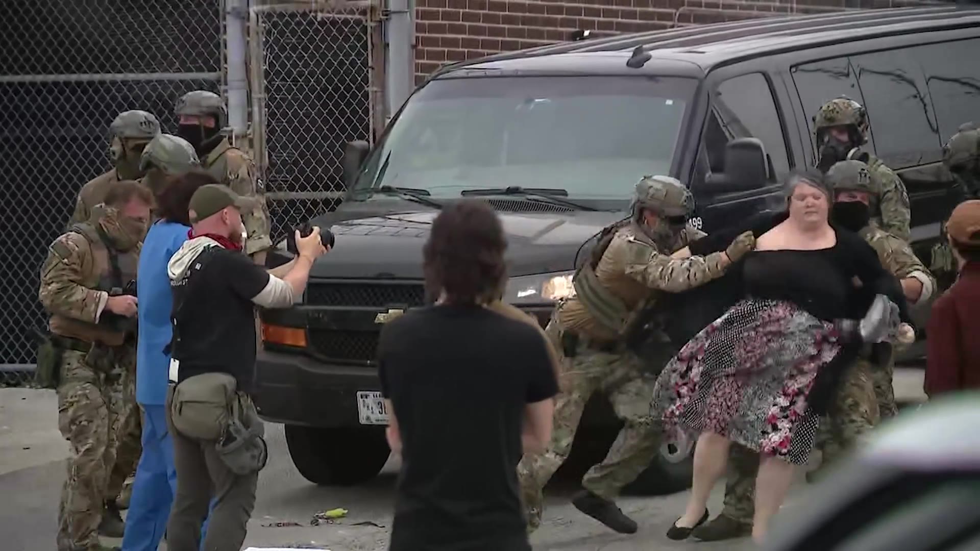 WindyDreamer312's tweet card. ICE protest escalates outside suburban Chicago facility. Video shows a woman thrown to the ground while blocking a vehicle, then getting face-to-face with agents before being arrested.