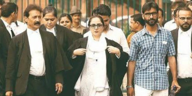 EmmaWatson's tweet card. "How often do we see a photograph like this? A confident, professional woman flanked by men who are not lecherously staring at her."