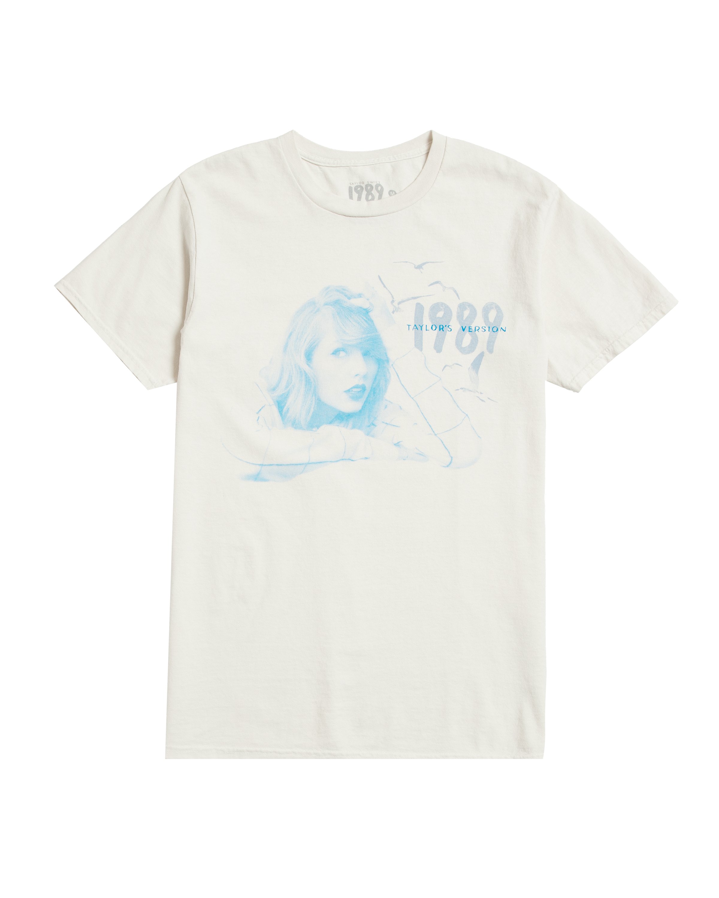 AlertsForMerch's tweet card. White t-shirt featuring from the vault photo of Taylor Swift, "1989 Taylor's Version" and seagull design printed on front. Standard fit.100% cotton Limit 10 per order. Taylor Swift® ©2023 TAS Rights...