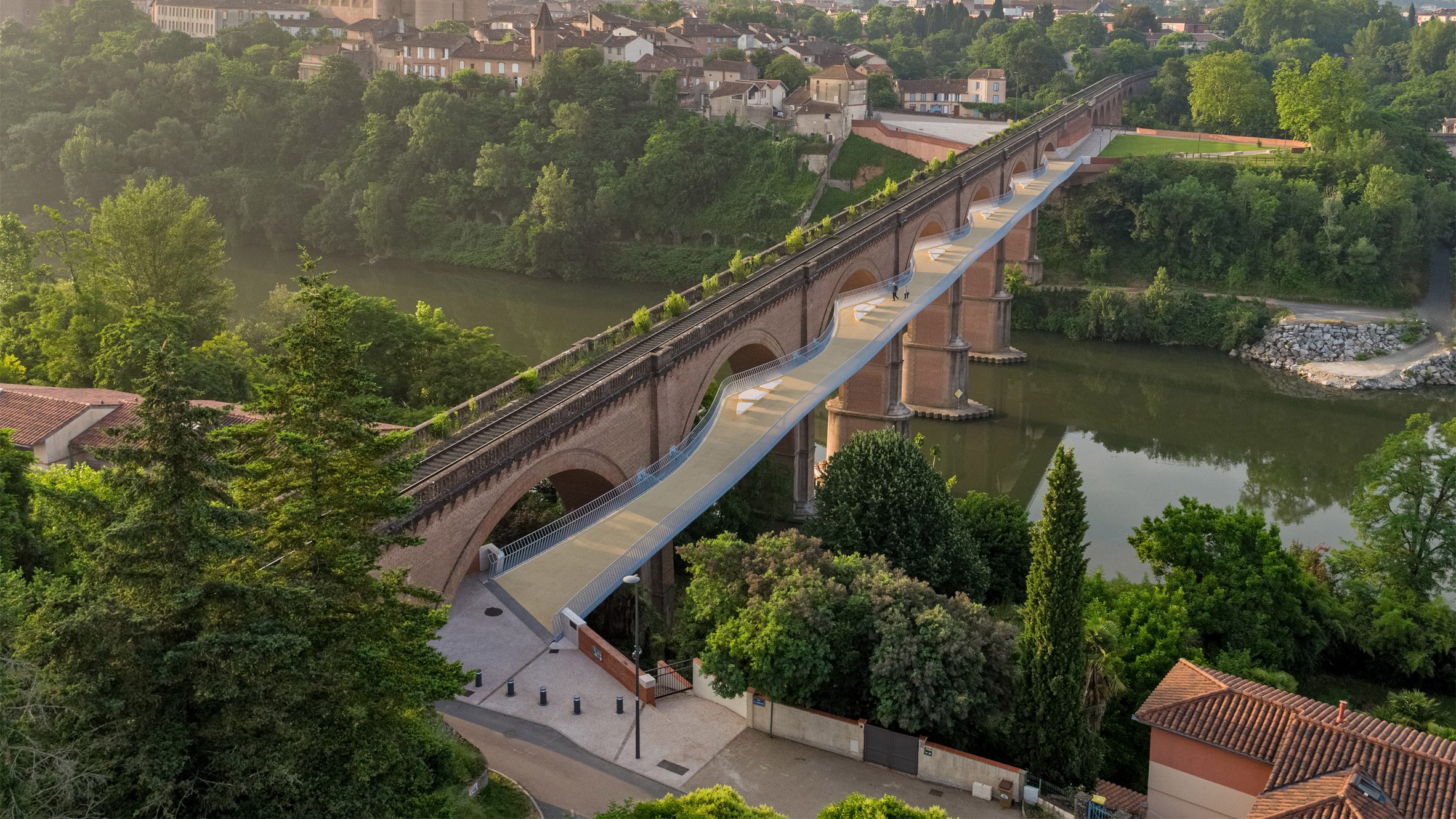 TimSloanDC's tweet card. Ney and Partners has created a sinuous pedestrian and bicycle bridge in Albi, France, which cantilevers from a 19th-century viaduct over the River Tarn.