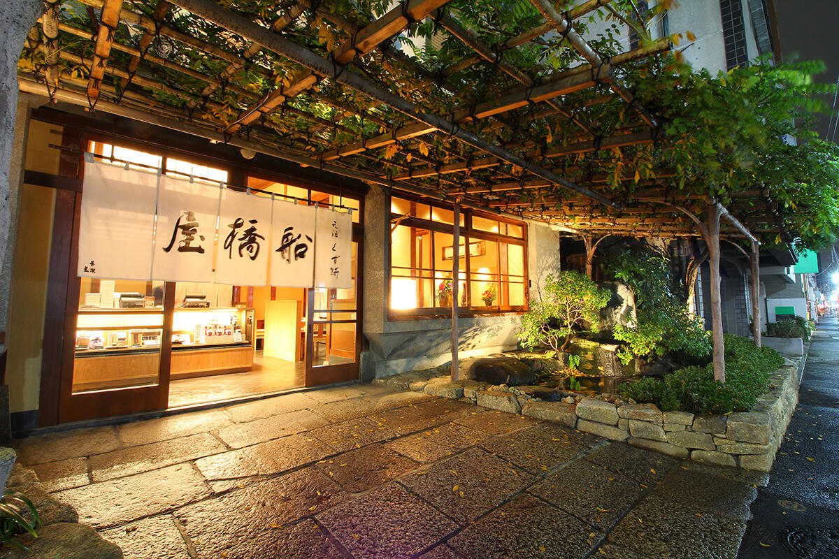 jcast_news's tweet card. 東京・亀戸で江戸時代に創業した和菓子屋の経営者から交通事故で罵声を浴び、車のドアを蹴られたとして、ツイッターに動画が投稿され、削除後も転載されて拡散している。事故は、この経営者が赤信号を無視したのが原因だったとされている。この和菓子屋「元祖くず餅船橋屋」は、会社サイトで事実関係を認め、「到底容認できるものではない」としてその行為を謝罪した。「どっから出て来てんだよ。えっ？じゃねーだろが」ドライバー