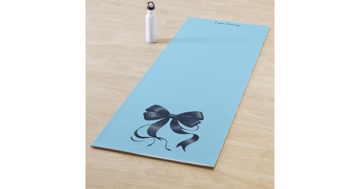 ShellsDesigns2's tweet card. A yoga mat in a shade of sky blue with the inspiring words 'I am Strong' at the top of the mat. A stylish navy blue coquette bow accents it. A great way to be inspired to stay fit and healthy! The...