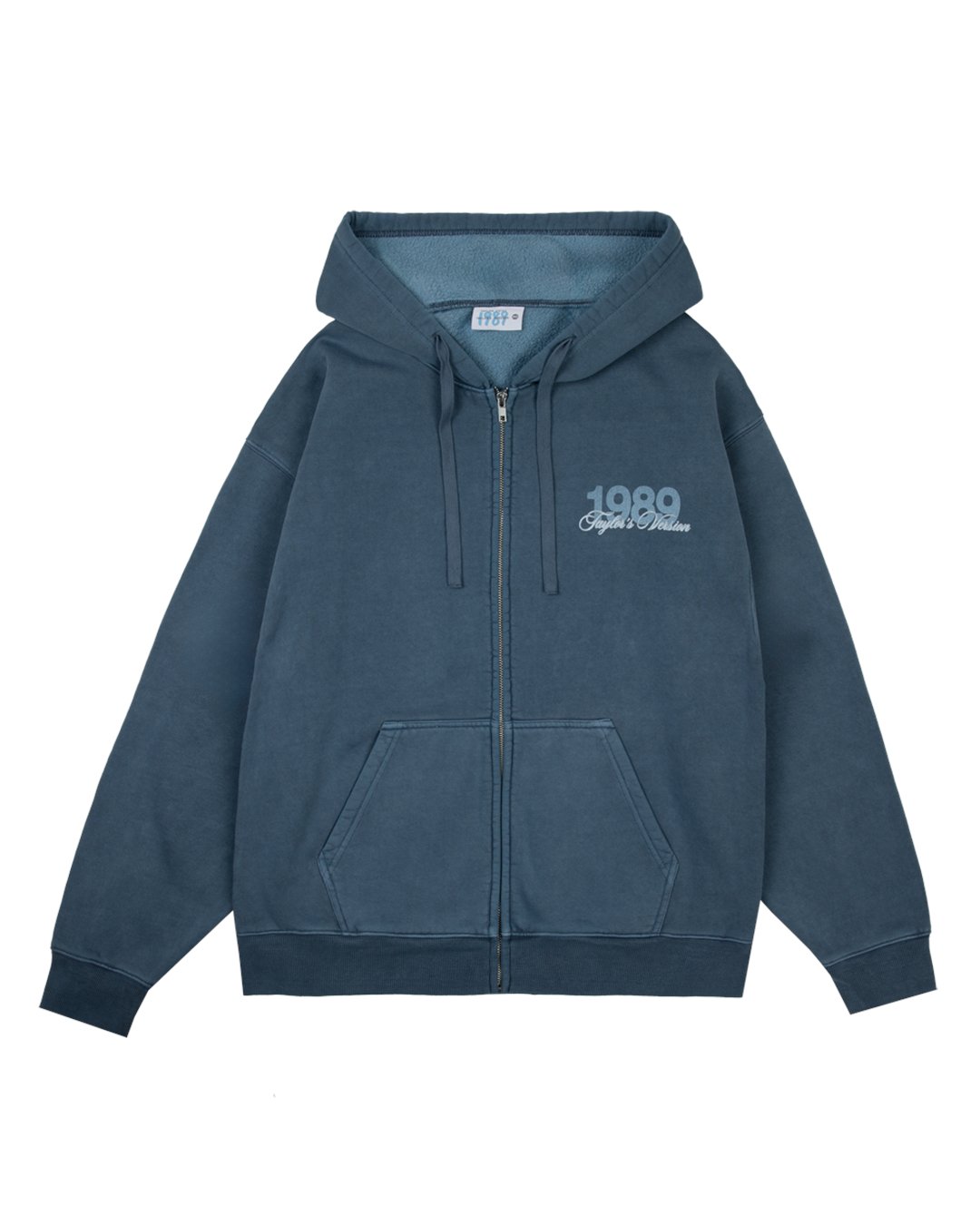 swiftpitch_py's tweet card. Washed blue zip up drawstring hoodie with front pockets featuring "1989 Taylor's Version" album title printed on wearer's front left chest with seagull design printed down wearer's right arm and "Is...