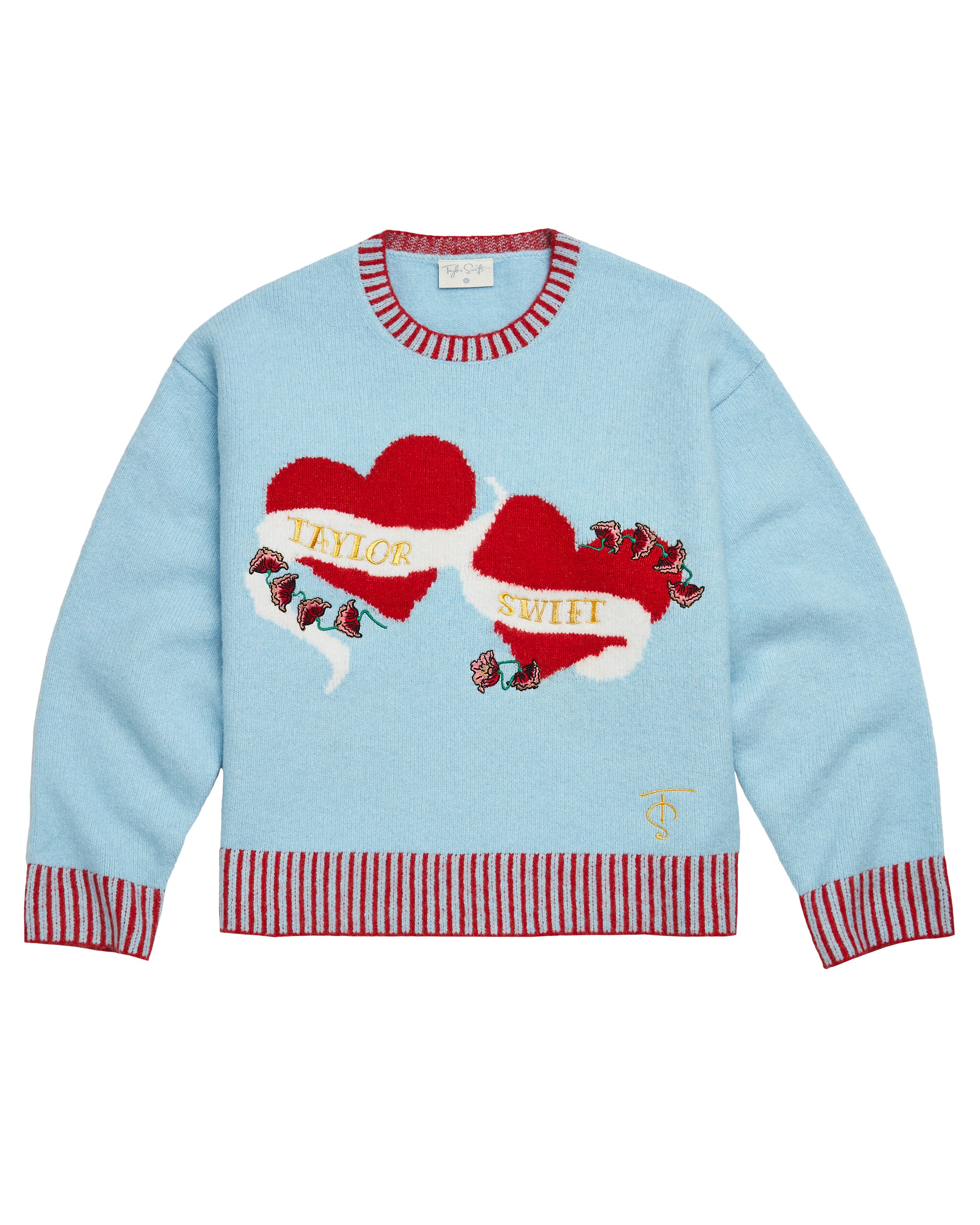 swiftpitch_py's tweet card. Blue sweater with red stripe trim featuring hearts knitted design on front with "Taylor Swift" logo and flower design embroidered on front and "TS" logo embroidered on wearer's left hem.Standard...