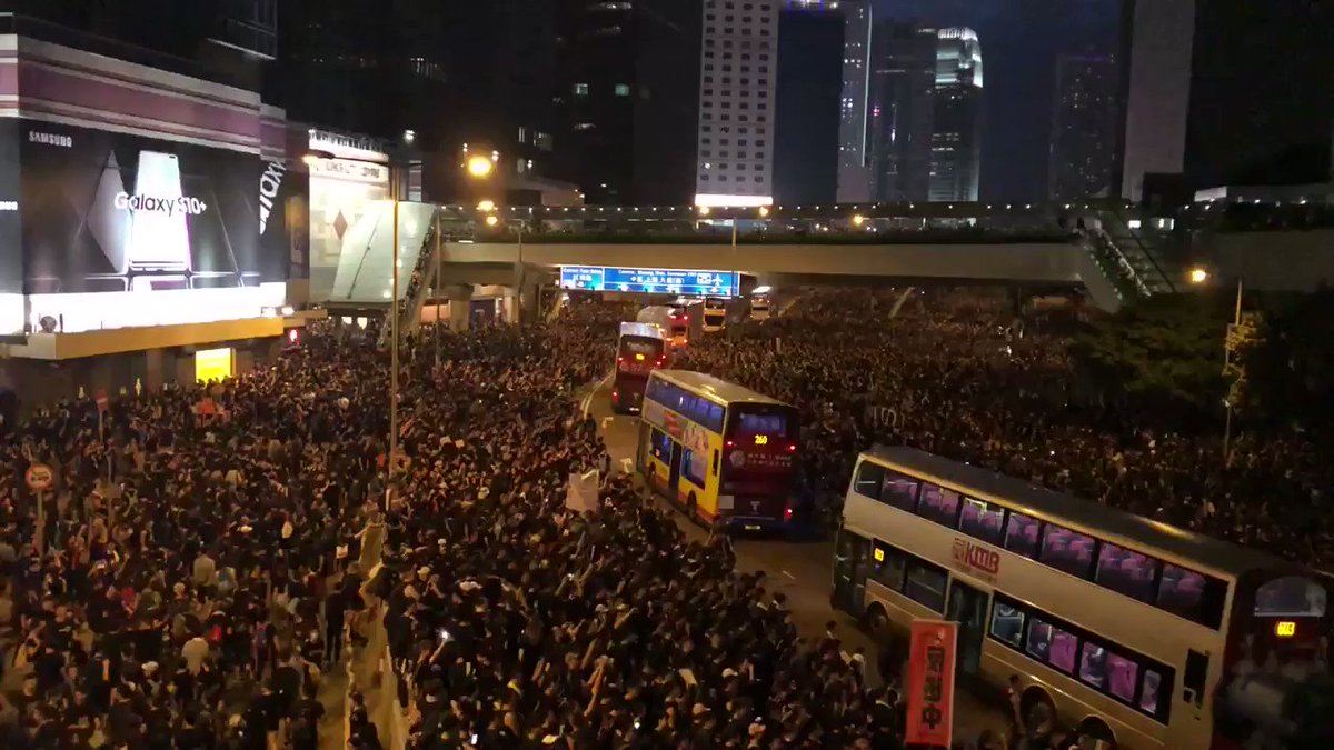 Amidst cheers, the crowd on Harcourt Road parts to allow buses through and then regathers behind them.