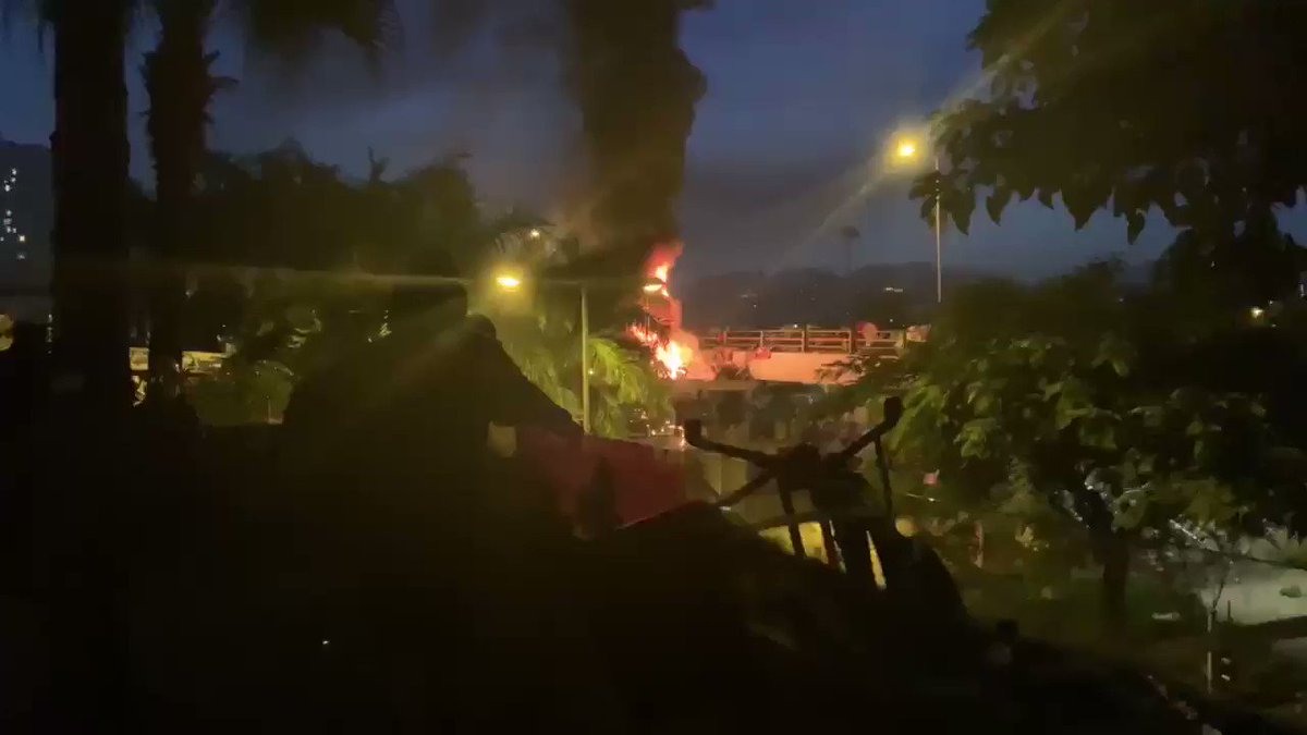A bonfire of chairs lit on a bridge. Many protesters had been sleeping in a sports hall when an alarm went off just before dawn and everyone sprung to their battle stations, explosions, bracing for riot police #HK #HongKongProtests #StandwithHK