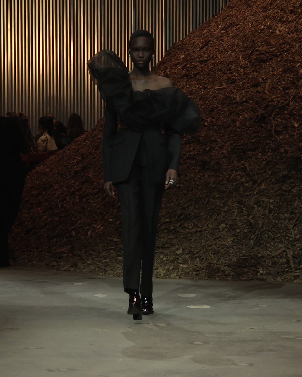 At the #McQueenAW22 show, Achenrin wears a black slashed single-breasted tailored jacket with a black tulle exploded neckline and elongated cigarette trousers.

See the full show: https://t.co/pDNw5U19py https://t.co/Q0NFF46YDb.