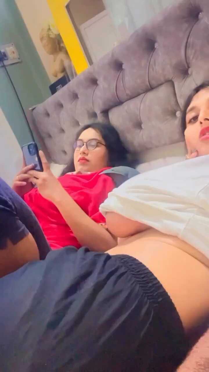 A woman seductively posing in a minimal outfit against a vibrant backdrop