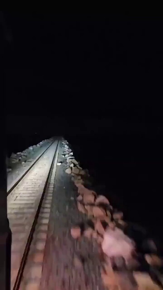 Train crossing a lagoon in midnight during a thunder storm. 