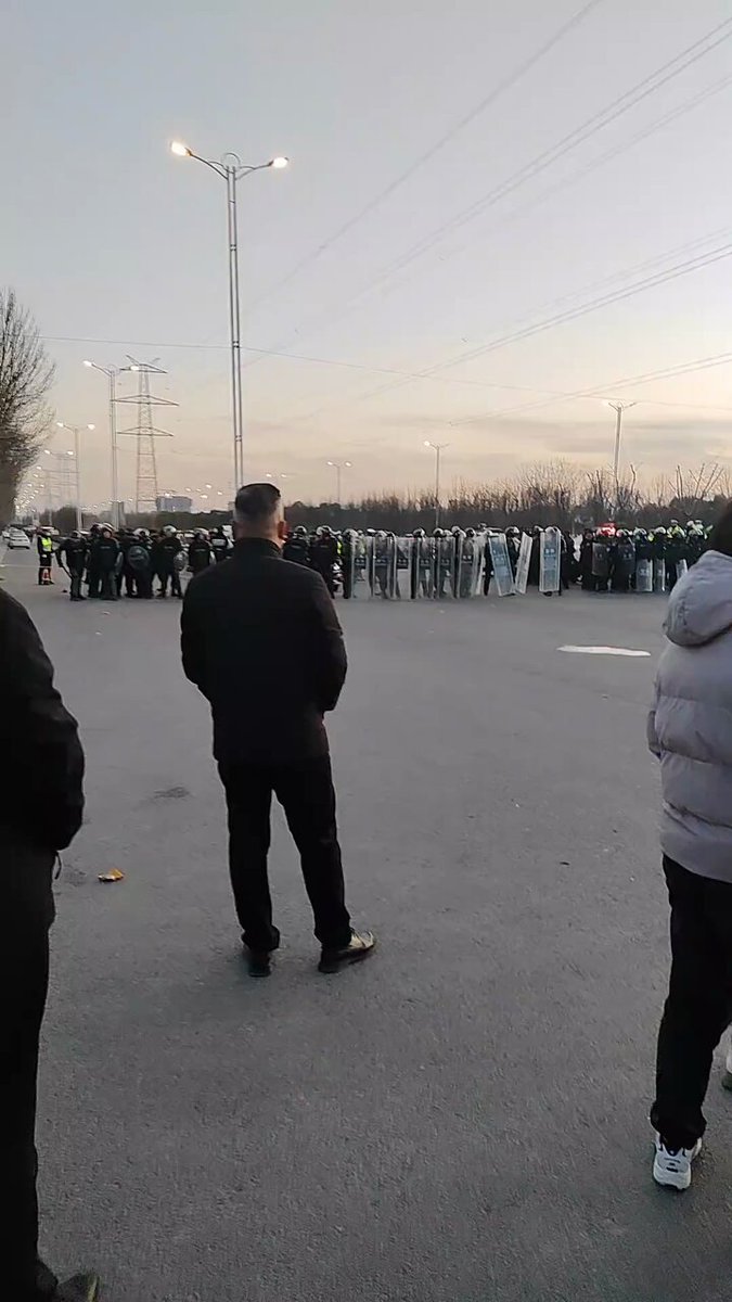 旁晚，民众们和全副武装的警察对峙。 