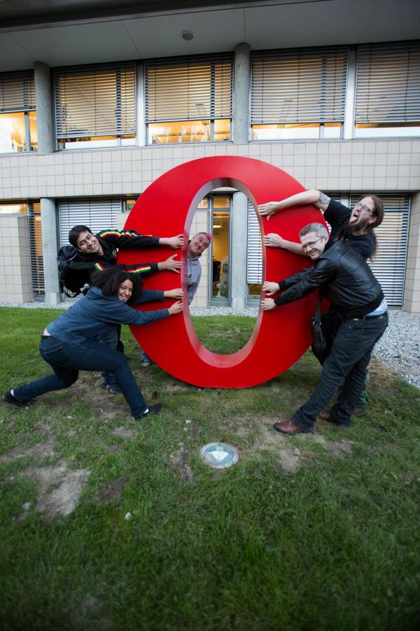 members of Opera's devrel team pull open a large red letter 'O' Opera logo
