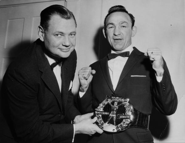 TheHickokBelt's tweet image. World welterweight boxing champion Carmen Basilio puts up his dukes  as Ray Hickok adjusts his 1957 Hickok Belt.