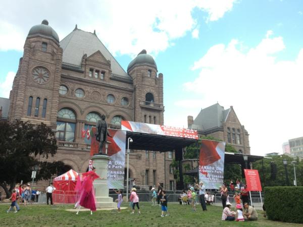 Colorful stilt dancer interacting with the children at Queen's Park Canada day celebration.