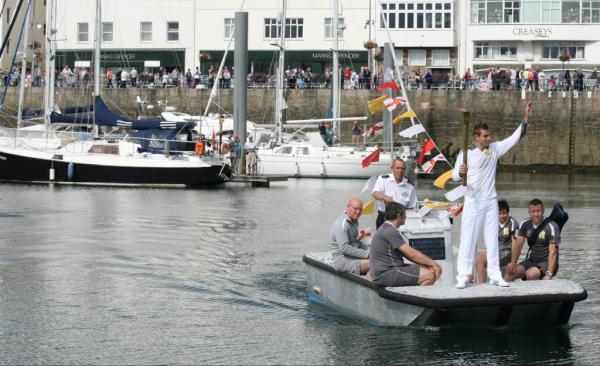 London2012's tweet photo. Pic: Torchbearer Luke Jones carries the Flame on a boat through St Peter Port on Day 58 of the #London2012TorchRelay http://t.co/OQjA6h6n