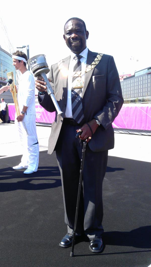 HannahBewley's tweet image. The Mayor of Brent holds an Olympic torch from 1948 on the podium. #torchrelay