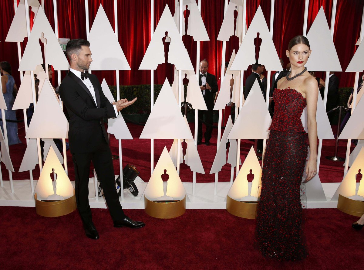 Adam Levine applauds his wife Behati Prinsloo on the Oscars red carpet