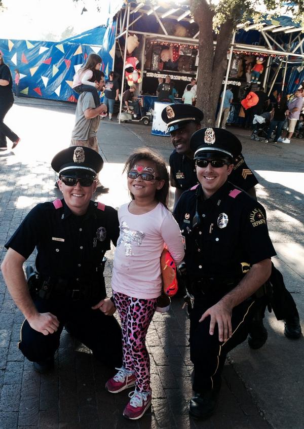DallasPD's tweet photo. Police posing in #Pink w/ face-painted fair goer @StateFairOfTX! @MitchDPD #Smile #DPDBigTex http://t.co/TcyCSfjEb3