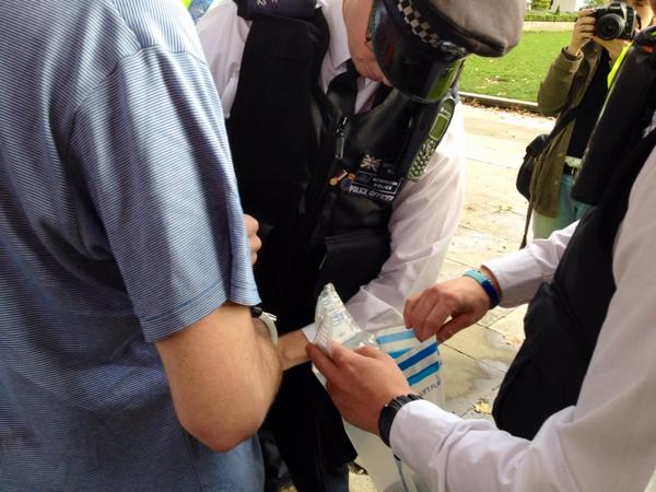 OccupyLondon's tweet photo. Arrestee having his things confiscated by police. #occupydemocracy http://t.co/Jt62x73pj3