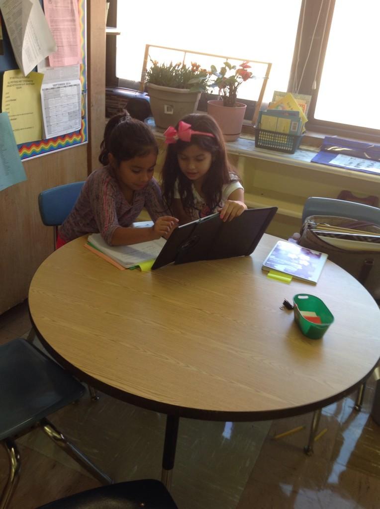 Estefani is teaching Ashley use an app.