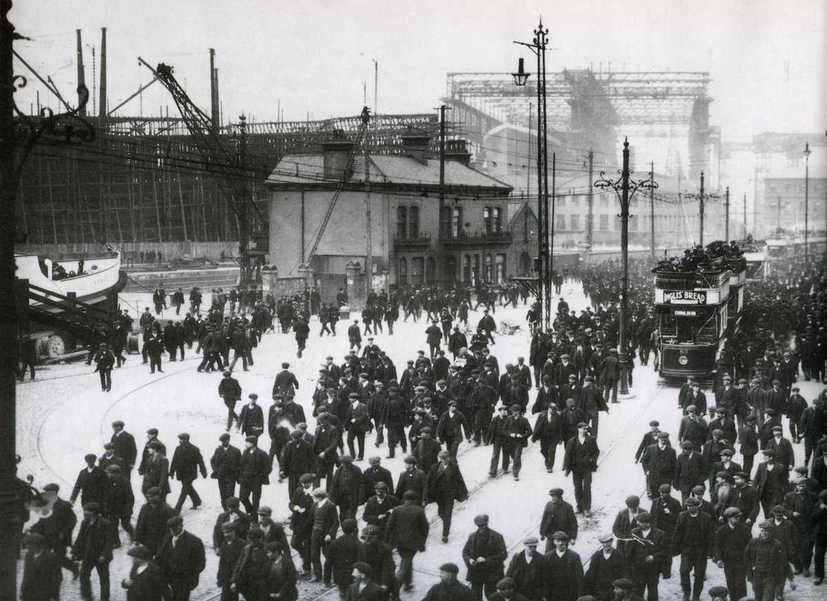 Workers leaving the Harland &amp; Wolff shipyard in early 1911. The RMS Titanic can be seen in the background,