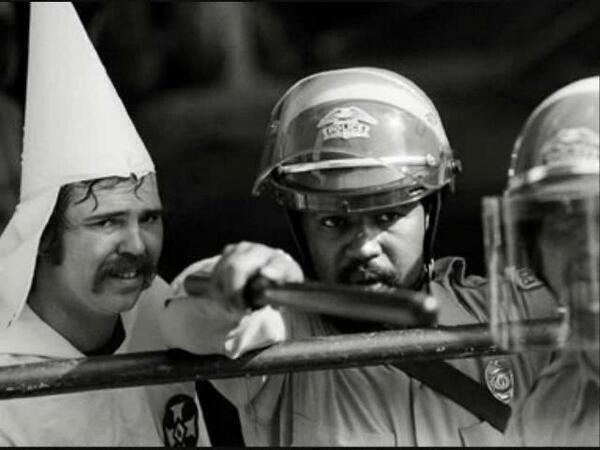A black policeman protects a KKK member, as protesters were closing in on them in at a rally in Austin, Texas, 1983
