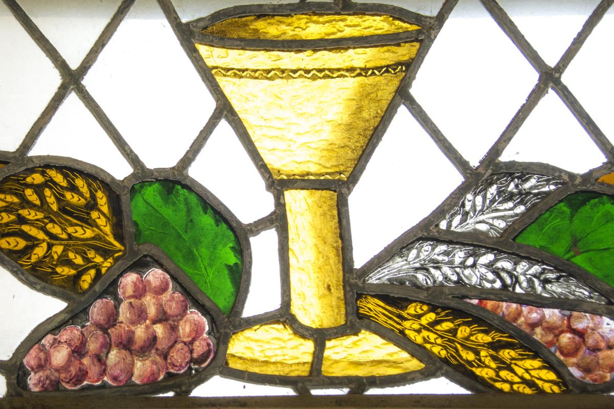 stained glass depicting a cup, grapes, and grain