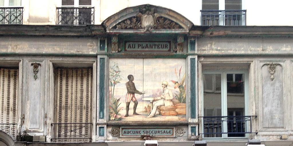 ParisOneForty's tweet image. Below a grey unforgiving winter sky on the Rue Montorgueil, a glimpse of French Colonialism that should be long gone.