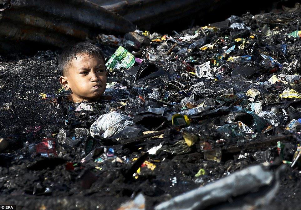 DailyMail's tweet photo. Philippine children search for charred belongings after fire tears through settlement http://t.co/IzeqDFlakO http://t.co/sJguk5JJ6E