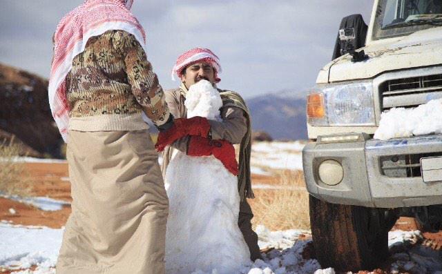 Saudi men make a snowman in the Aleghan Heights, in the Tabuk region